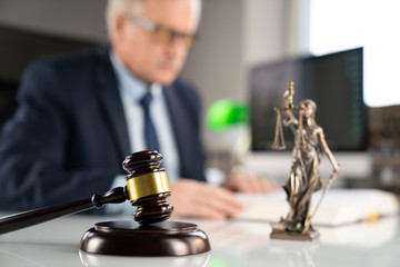 Consultation with a lawyer concept.  Mallet, Themis statue and documents on the glass table.