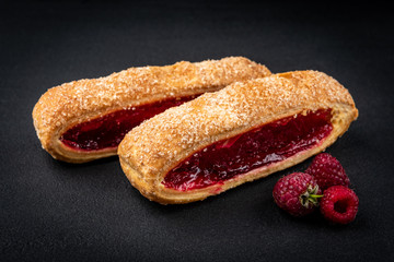Puff pastry with cherry or raspberry jam ion black background.