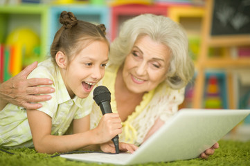 Portrait of grandmother and daughter singing karaoke