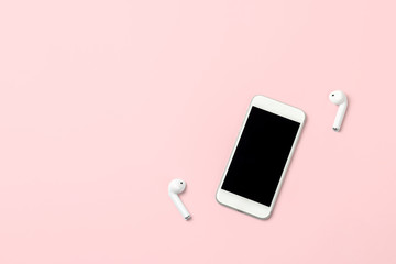 Smartphone and wireless headphones on bright pink background