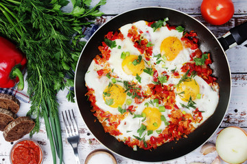 Shakshouka with five cooked eggs on top of tomato sauce in cast iron skillet	