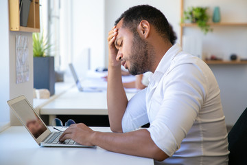 Closeup shot of tired office worker. Exhausted African American man rubbing forehead. Overwork concept