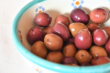 Typical Italian and Apulian salty and briney olives cured with an aromatic herb brine of rosemary, bay leaves and thyme, traditional snack or appetizer in a terracotta pot
