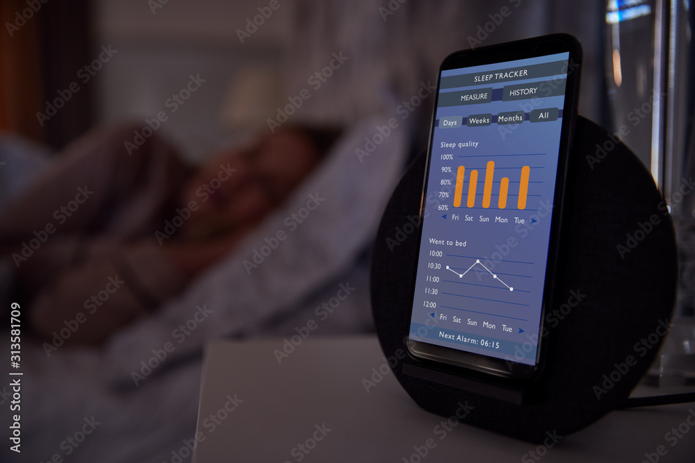 Wall mural woman sleeping in bed with sleep data app running on mobile phone on bedside