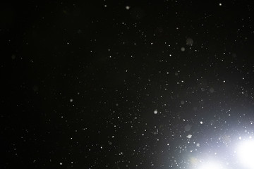 Snow and bokeh in the light of a lantern on a black background