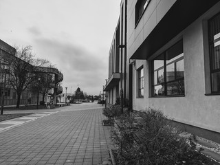 Urban town area passage next to a modern building during a cloudy weather showing an everyday life in town and doing the paperwork in black and white