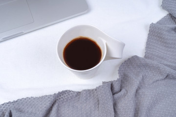 Office workspace with cup of coffee, laptop, knit a blanket on white background.