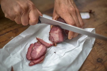 Detailed view of a hand slicing homemade pork chorizo on wooden table