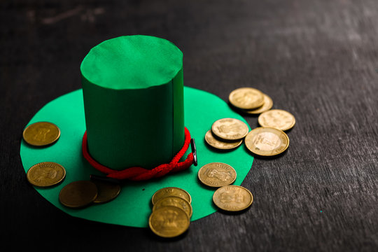 Happy St Patricks Day green leprechaun hat with gold covered chocolate coins on dark wood background, with applied retro style faded filters.