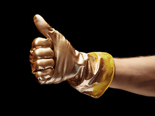 Image of gold painted Like gesture of hand in yellow rubber glove on black background