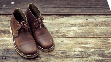 Brown stylish boots on wood background,  retro color