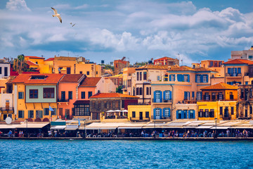Fototapeta na wymiar Old port of Chania with flying seagulls. Landmarks of Crete island. Bay of Chania at sunny summer day, Crete Greece. View of the old port of Chania, Crete, Greece. The port of chania, or Hania.