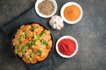 Chicken tikka masala traditional Asian spicy meat food with rice tomatoes and cilantro in a black bowl on dark background. Top view.