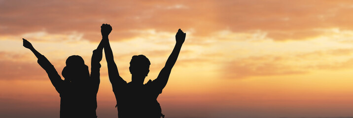 Successful Asian couple open arms raised on sunrise with sky. Rear view.