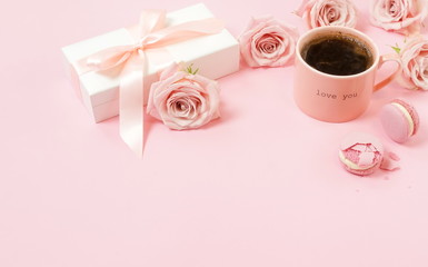 Valentine's day background. Gift box, pink cup of coffee, pink roses and pink macaroons on pink background. Copy space