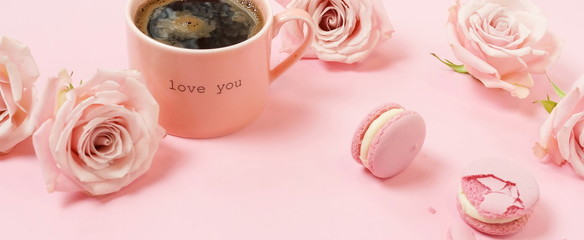 Valentine's day background banner. Pink cup of coffee, pink roses and pink macaroons on pink background. Copy space