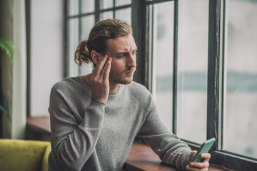 Young bearded handsome man in grey looking tired