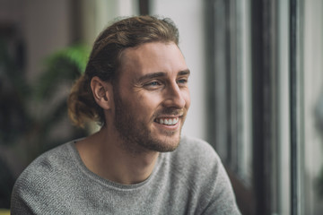 Young bearded handsome man in grey looking happy