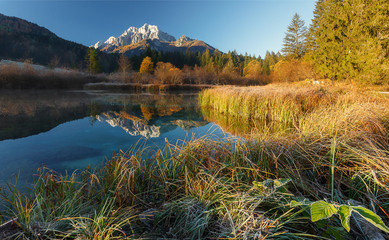 Awesome alpine lake with reflection during sunrise. Stunning Frosty Morning on mountain lake...