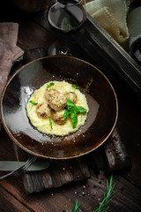 Beef meatballs with risotto in cream sauce in a plate on a wooden background. Italian cuisine rustic style