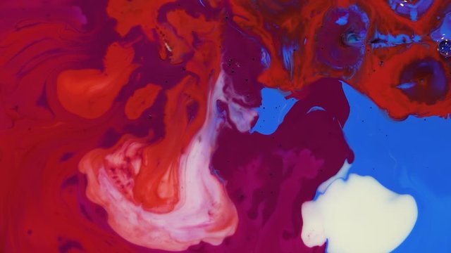 Bright colorful acrylic paints mix into abstract pigments in slow motion. Abstract color moving background close up macro