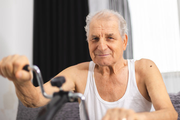 Senior man make physiotherapy for joints in the hands at a home medical device