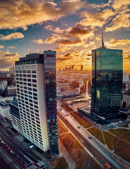 Beautiful panoramic aerial drone view to the Сenter of modern Warsaw city with silhouettes of skyscrapers in in the rays of the setting winter January sun - amazing sunset, Poland