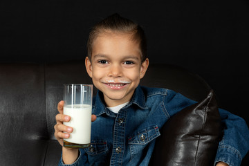 little boy drinking milk on black background