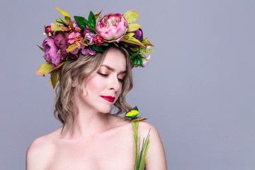 tender young woman posing in flower wreath with artificial  greenbutterfly,  isolated on grey