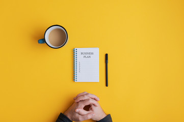 Man sitting by spiral notebook with Business plan ideas ready to be written in it