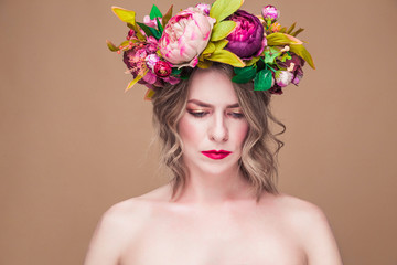 beautiful young woman model with bright flowers on her head on the ocher color background