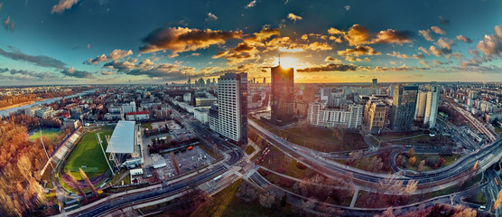 Beautiful panoramic aerial drone view to the Сenter of modern Warsaw city with silhouettes of skyscrapers in in the rays of the setting winter January sun - amazing sunset, Poland