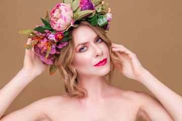 beautiful young woman model with bright flowers on her head on the ocher color background