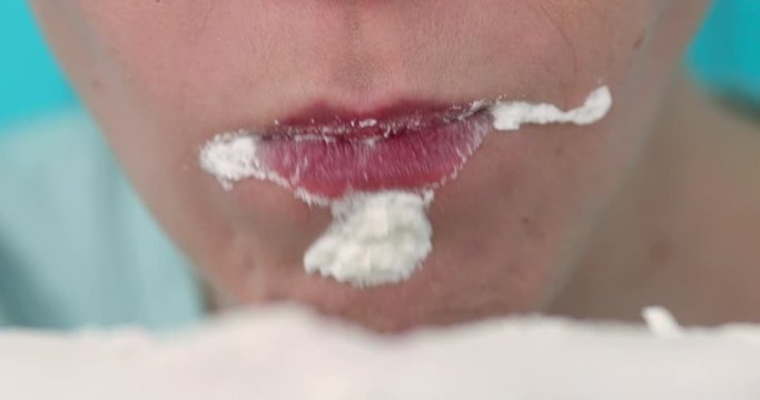Close up of crop faceless woman opening mouth for biting off homemade white birthday cake
