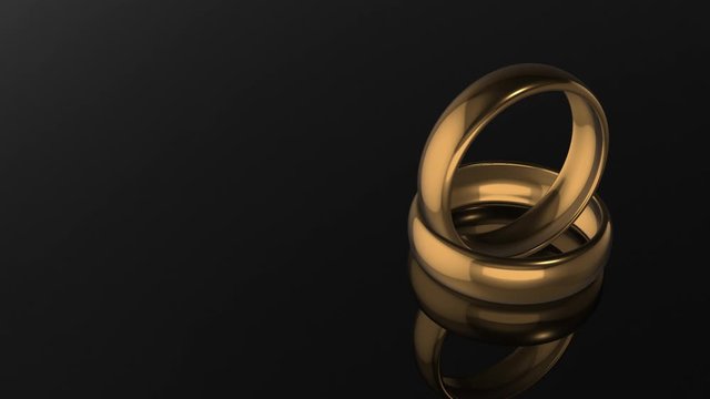3D rendering.Two gold wedding rings on black background, loopable