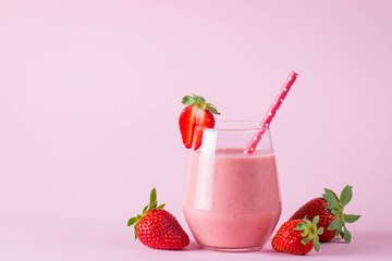 Glass of fresh strawberry milkshake, smoothie and fresh strawberries on pink, white and wooden...
