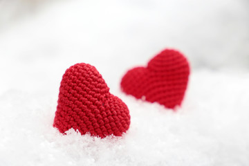 Fototapeta premium Love hearts, Valentine's card, two red knitted symbols of passion in the snow. Background for romantic event, celebration or winter weather