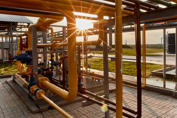 Fototapeta na wymiar Pipeline system at gas processing plant lit by sunset sun