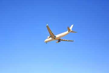 Commercial jet airplane flight on blue sky background. Seen from below.