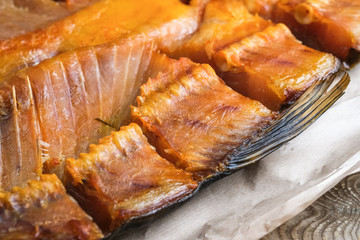 Cut smoked fish on craft paper on rustic background. Close-up.