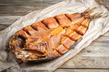 Cut smoked fish on craft paper on rustic background. Close-up.