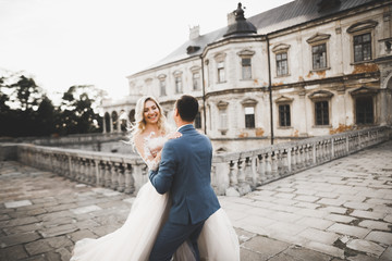 Naklejka premium Beautiful bride and groom embracing and kissing on their wedding day outdoors