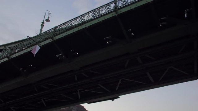 Boat departure by the river POV under the Liberty Bridge dusk evening cityscape view Elisabeth Bridge Budapest Hungary