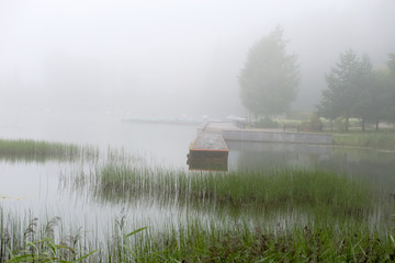 Granite embankment of a forest lake on an early foggy morning