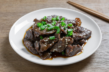 close up of stir fried beef with teriyaki sauce in a ceramic dish on wooden table. asian homemade style food concept.