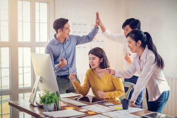 Group of young asian designers giving high five on the success of website design and application on...