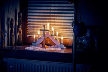 Symbols of the Nativity of Christ in a residential interior: candles, cross with a crucifix, Menorah (temple lamp), festive Christmas illumination