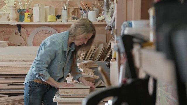 Female carpenter makes an furniture at a little workshop.