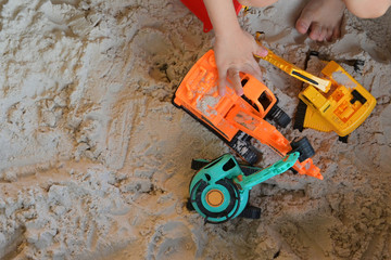child boy play construction vehicle toy in sand playground