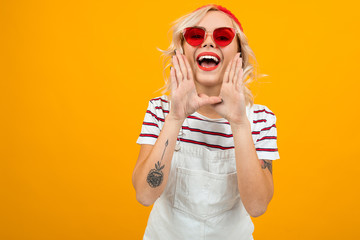 charming sexy blonde girl in a stylish look yells something on a yellow background